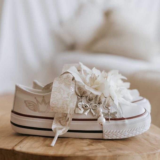 Sneaker de algodón con estampados de corona en laminado de plata. Los cordones son en forma de lazada de estampada con motivo de encaje en color beige suave. Ideales para eventos especiales, bodas y comunión.