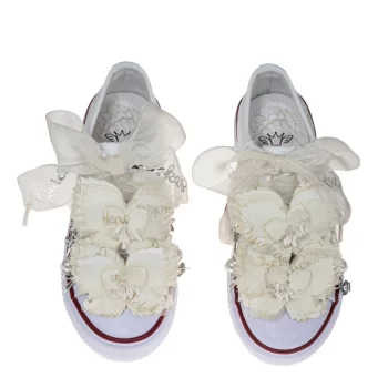 Sneaker de algodón con puntera con estampado de mariposas en los laterales de color beige suave. Realizadas a mano, lleva dos mariposas de organza y crepe en la parte superior con pasador para que se puedan quitar y volver a colocar. Los cordones son en forma de lazada de organza en color natural con detalle de laminado QUICKAS. A ambos lados lleva abalorios con acabado plateado y adorno de perlas con anillas para que puedas poner y quitar.