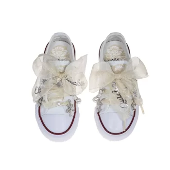 Sneaker de algodón con estampados de encaje en los laterales de color beige suave. Los cordones son en forma de lazada de organza en color natural. Ideales para eventos especiales, bodas y comunión.