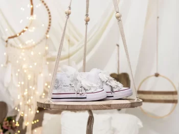 Botas de algodón con puntera con estampados de mariposas en los laterales de color gris perla. Están realizadas a mano, lleva mariposas de organza y crepe en la parte superior. Los cordones son en forma de lazada de organza en color blanco con detalle de laminado QUICKAS.