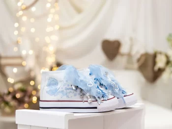 Botas de algodón con puntera con estampados de mariposas en los laterales de color cielo. Están realizadas a mano, lleva mariposas de organza y crepe en la parte superior. Los cordones son en forma de lazada de organza en color blanco con detalle de laminado QUICKAS.
